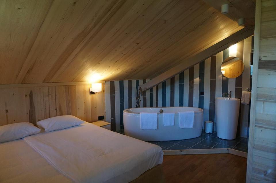 ein Schlafzimmer mit einem großen Bett und einer Badewanne in der Unterkunft Maison d'hôtes La Barmaz in Combloux