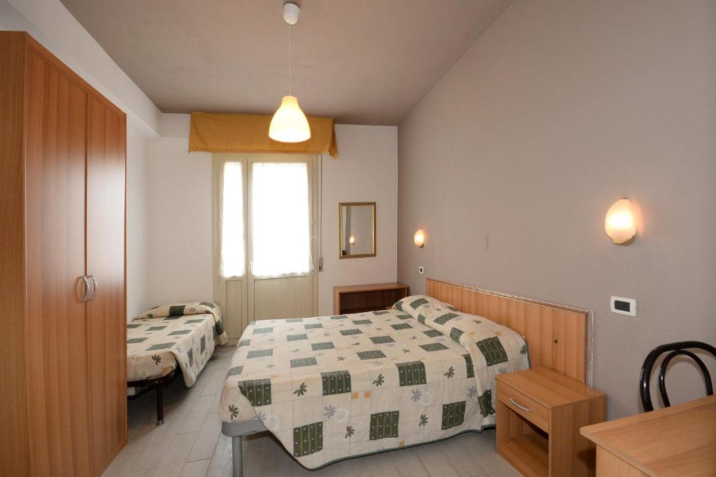 1 dormitorio con 2 camas, mesa y ventana en Hotel Al Ragno, en Cesenatico