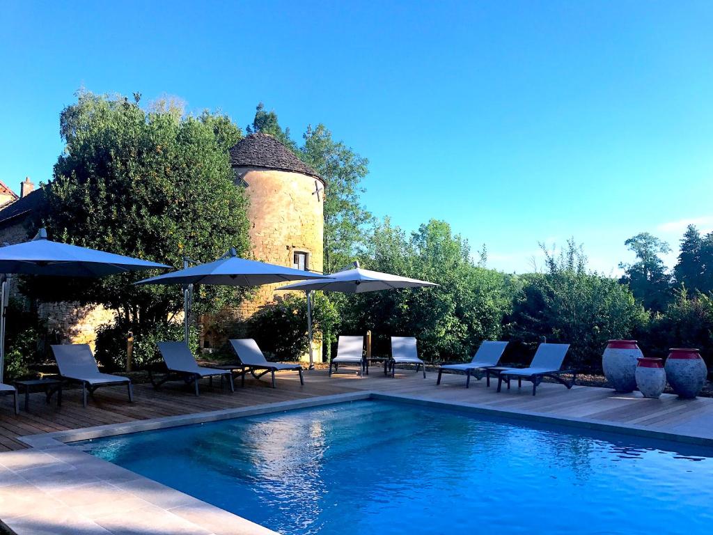 une piscine avec des chaises et des parasols ainsi qu'une tour dans l'établissement Château D'igé, à Igé