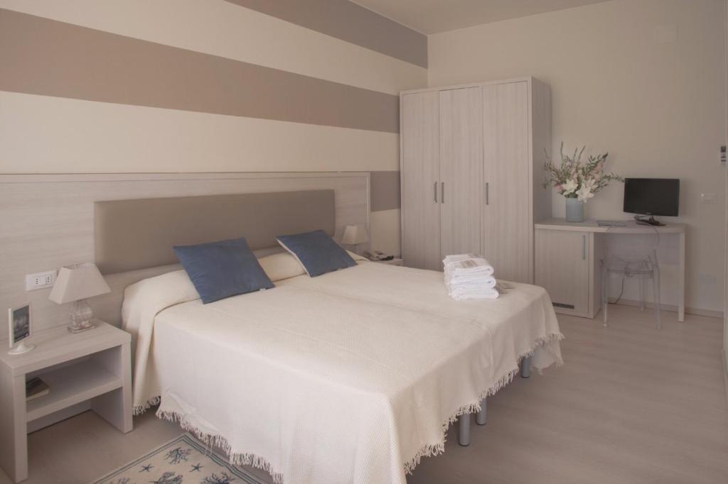 a bedroom with a large white bed with blue pillows at Locanda Kon Tiki in Alassio