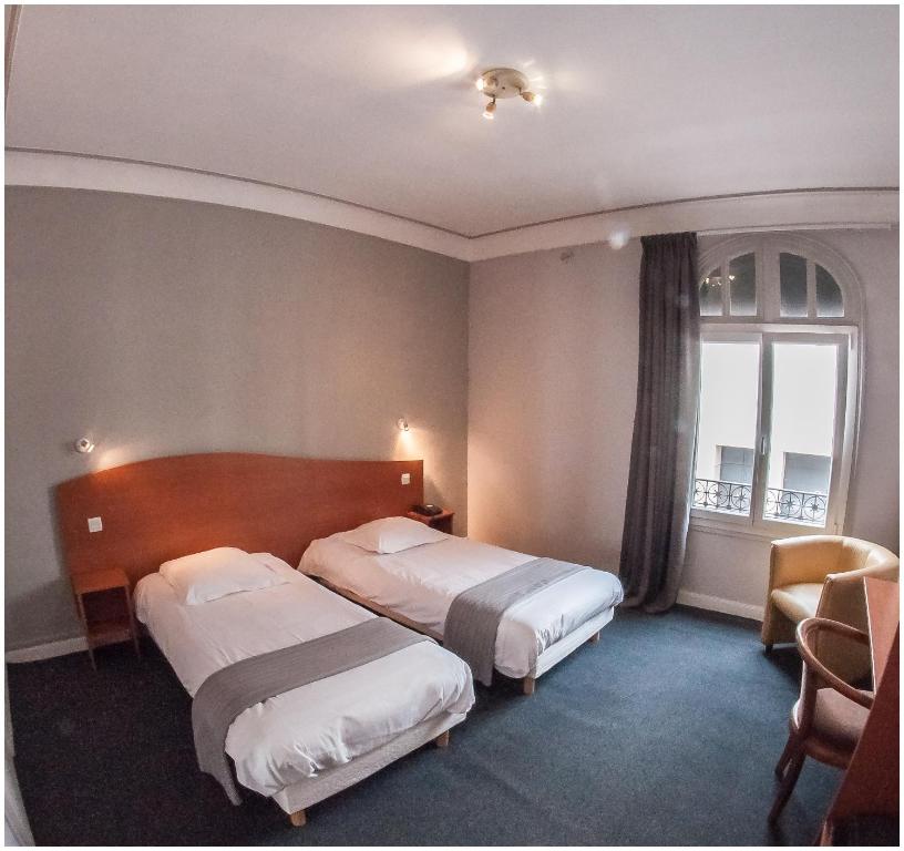 a hotel room with two beds and a window at Hôtel Gambetta in Reims