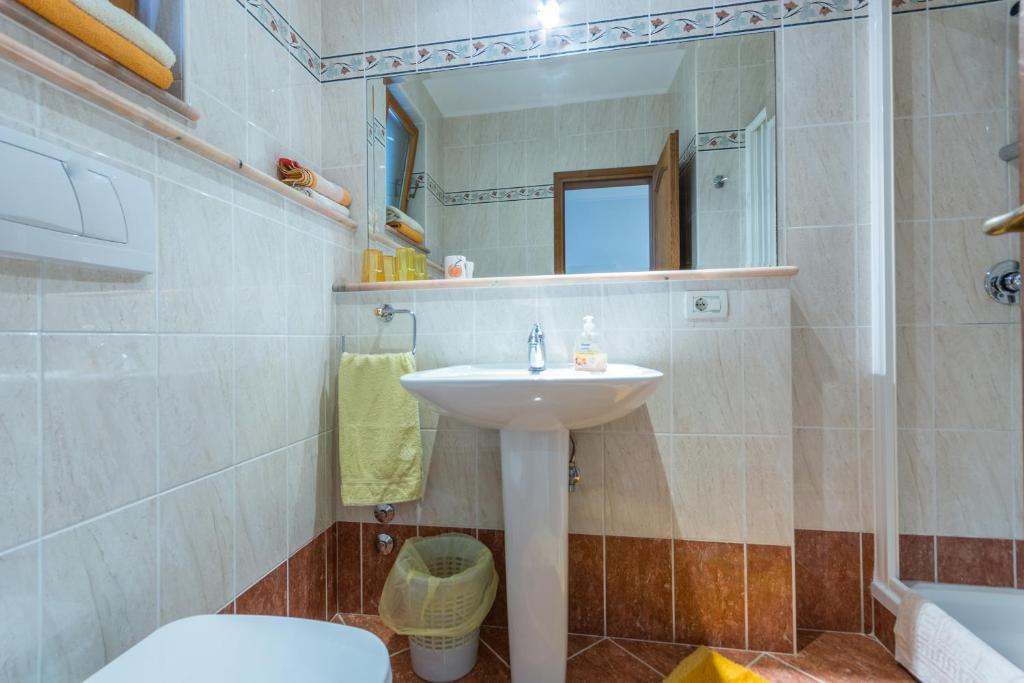 a bathroom with a sink and a toilet and a mirror at Guesthouse Casa Nova in Poreč