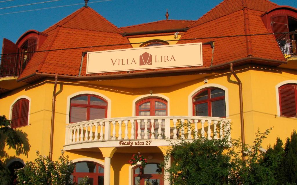 un bâtiment jaune avec un panneau indiquant la villa niuto dans l'établissement Villa Lira, à Hévíz