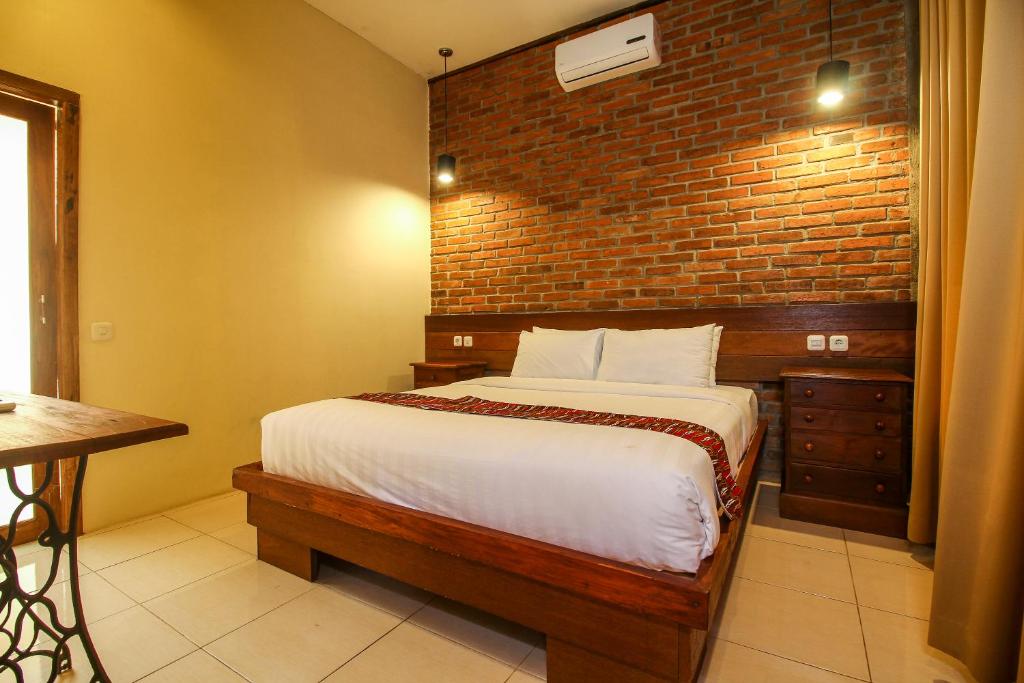 a bedroom with a bed and a brick wall at Cempaka Villa II in Borobudur