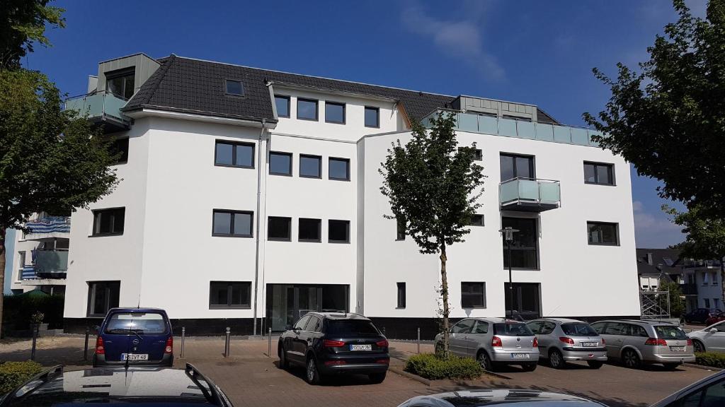 ein weißes Gebäude mit Autos auf einem Parkplatz in der Unterkunft Cloud 7 II in Heinsberg