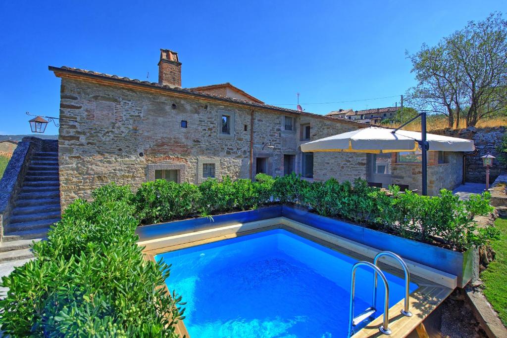 una piscina frente a una casa de piedra en La Fonte by PosarelliVillas, en Cortona