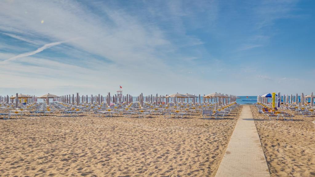 a row of beach chairs and umbrellas on a beach at Unico Hotel Caorle in Caorle