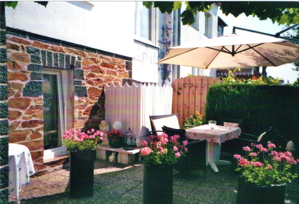 a patio with a table and an umbrella and flowers at Ferienwohnung Büttner in Solms-Oberbiel