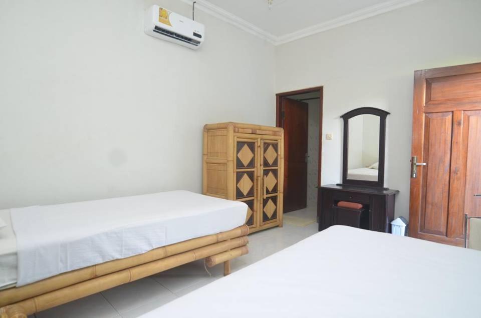 a bedroom with two beds and a dresser and a mirror at Puri Itoma Bungalows in Kuta Lombok