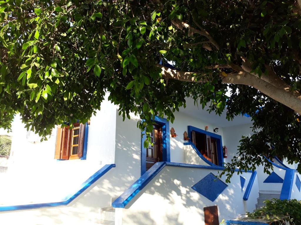 a white building with blue doors and a tree at Paradise Studios in Lipsoi