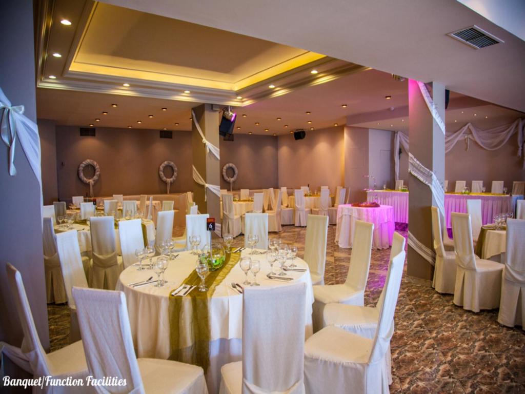a banquet hall with white tables and white chairs at Galini Palace in Athens
