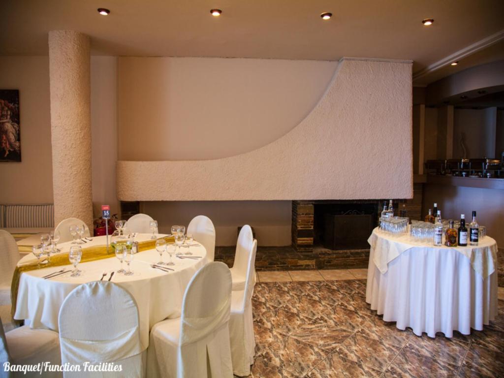 a large room with white tables and chairs and a large screen at Galini Palace in Athens