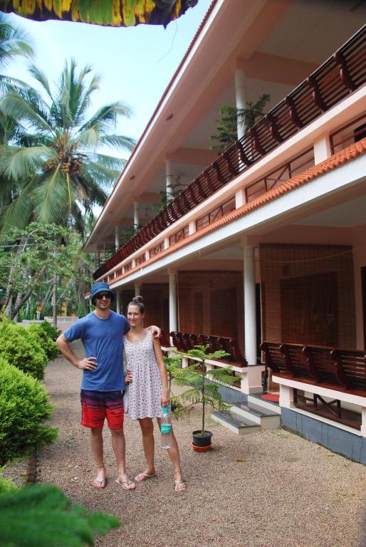 a man and a woman standing in front of a building at Hotel Cocobeach Kovalam in Kovalam