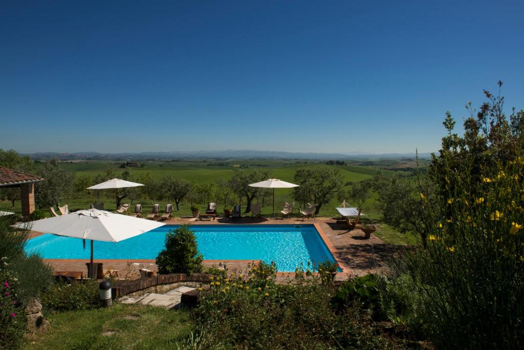 a swimming pool with umbrellas and a view of the countryside at Villa Giuncheto in Corsano
