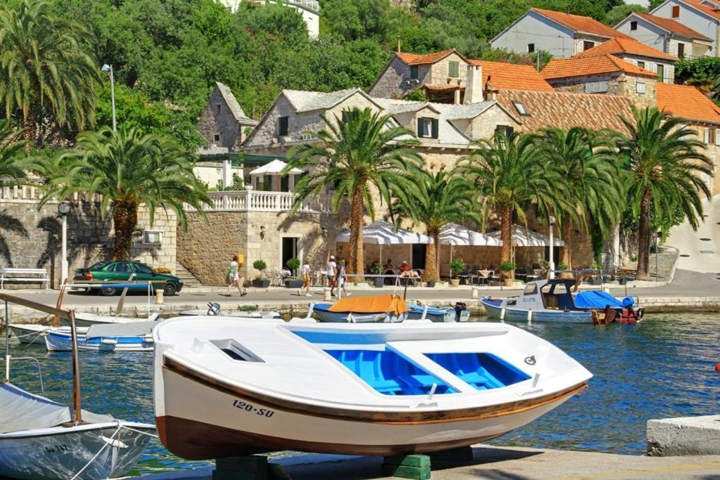 a boat is docked in a harbor with palm trees at Vila Marija in Supetar