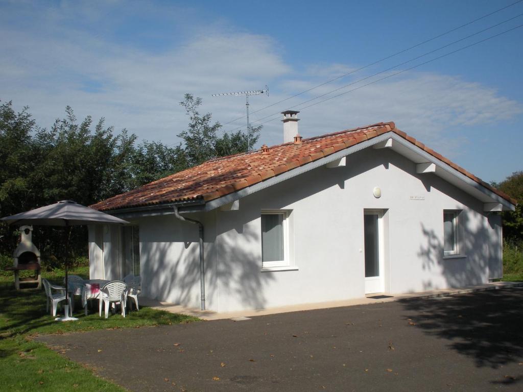 mały biały dom z dwoma krzesłami i parasolem w obiekcie Four À Pain w mieście Louer