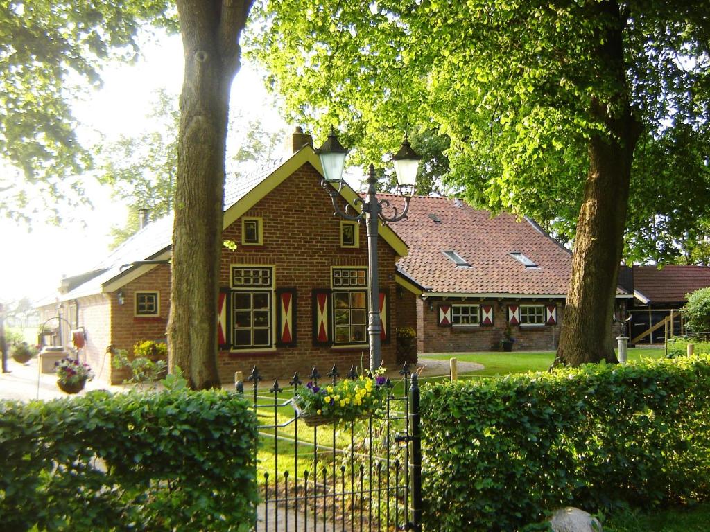 a house with trees and a fence in front of it at Bed en Breakfast De Boksloot in Ravenswoud