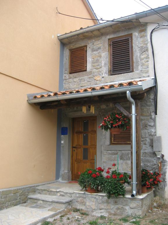 un edificio con flores delante de una puerta en Antonia & Arian en Roč