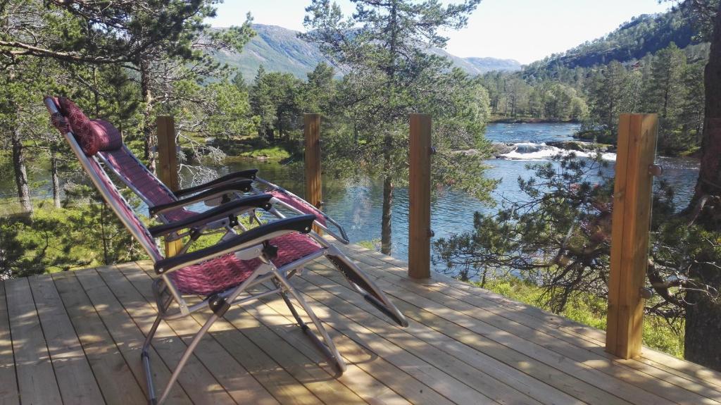 two chairs sitting on a deck with a view of a river at Hytte ved Gaularfjellet in Viksdalen