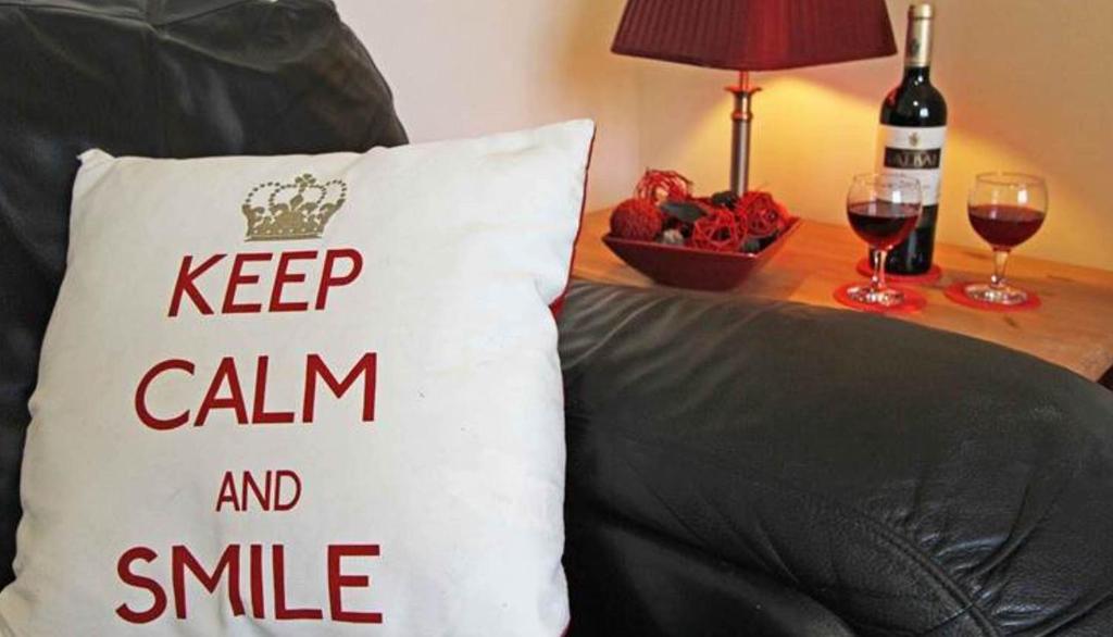 a keep calm and smile pillow on a couch with wine glasses at Sea Haven Northumberland in Seahouses