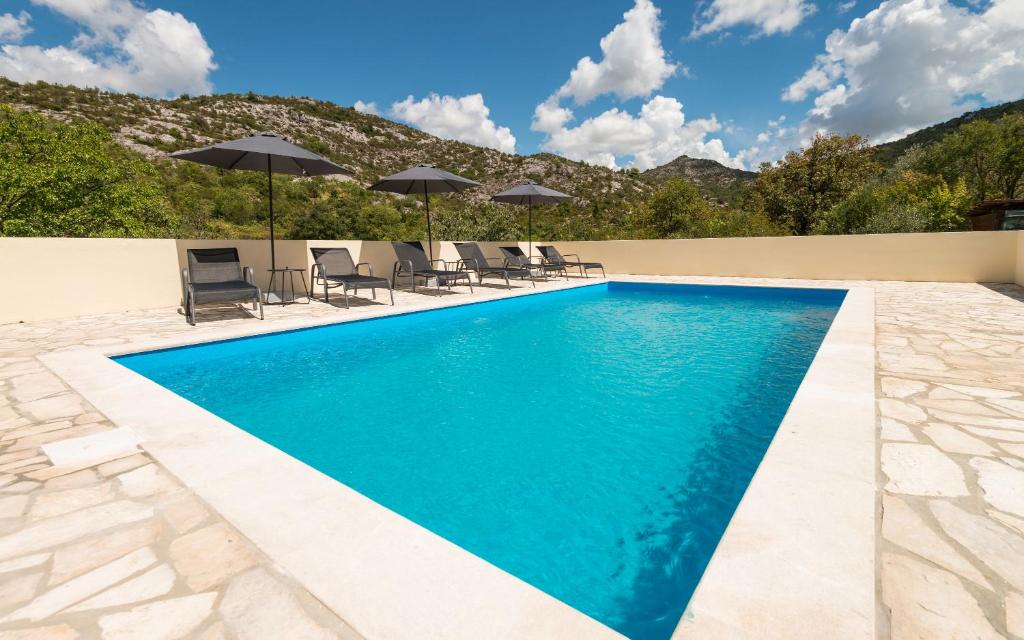 a swimming pool with chairs and umbrellas at Agrotourism Matusko in Neum