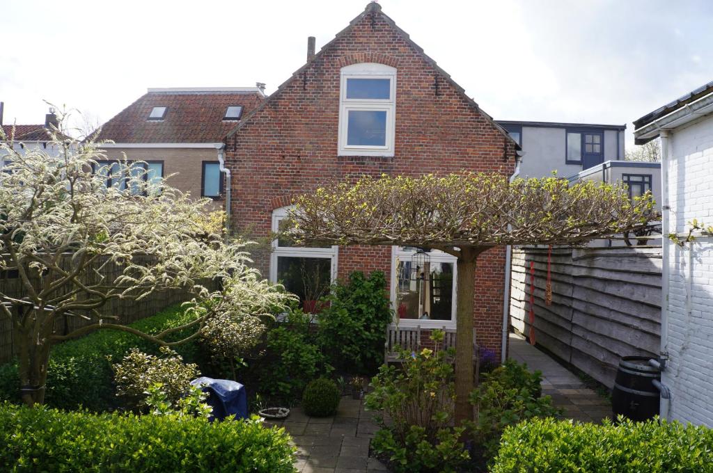 a brick house with a tree in the front yard at het Bakkershuisje in Colijnsplaat