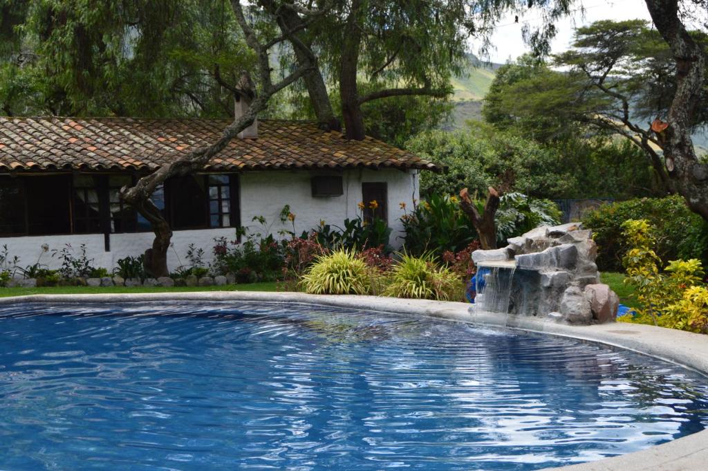 a swimming pool with a waterfall in front of a house at Hacienda San Francisco in Tumbabiro