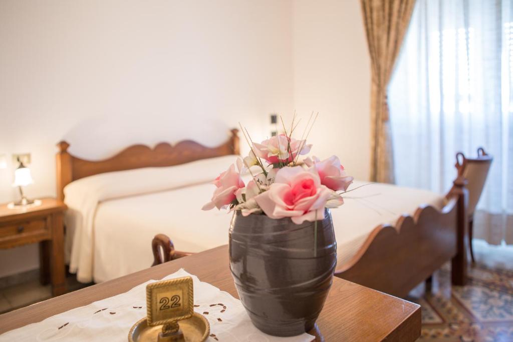 eine Vase mit Blumen auf einem Tisch im Schlafzimmer in der Unterkunft Hotel AeR BJ Vittoria in Cagliari
