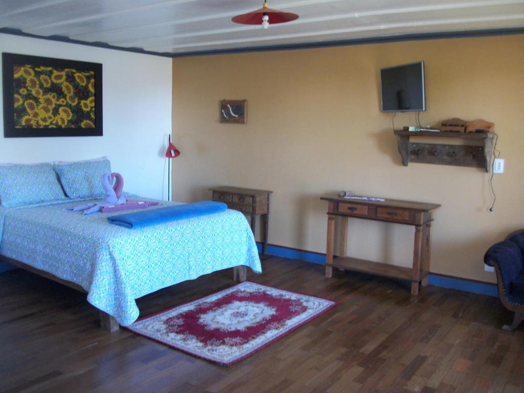 a bedroom with a bed and a table and a tv at Chales das Andorinhas in Lavras Novas