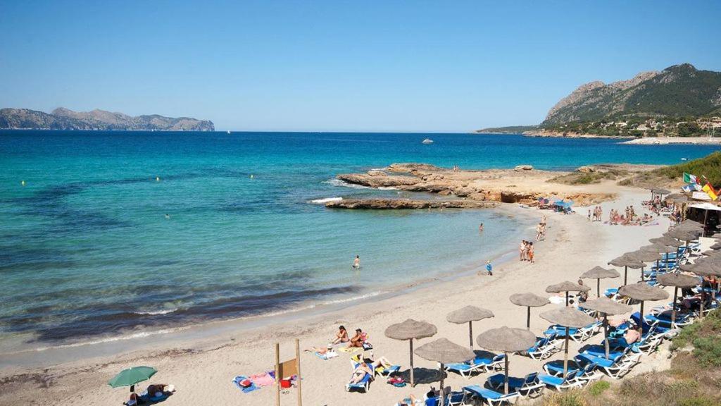 a beach with umbrellas and people on the beach at Casa Coromines in Alcudia