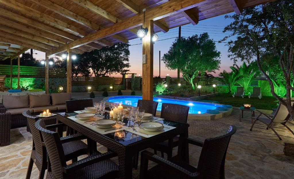 Un patio con mesa y sillas y una piscina. en Villa Feronia, en Hersonissos