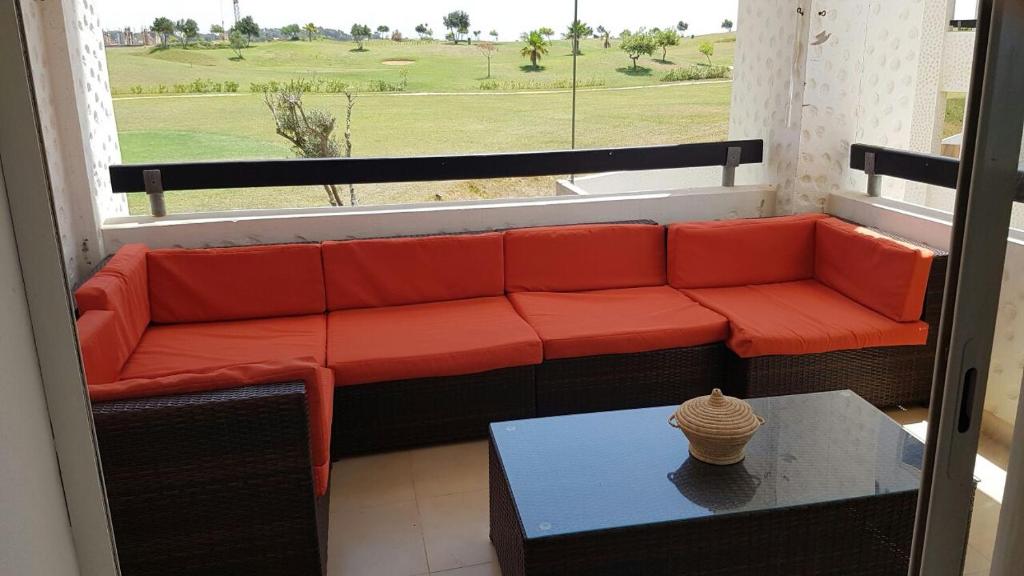 um sofá vermelho sentado num quarto com uma janela em Assilah marina golf em Arzila