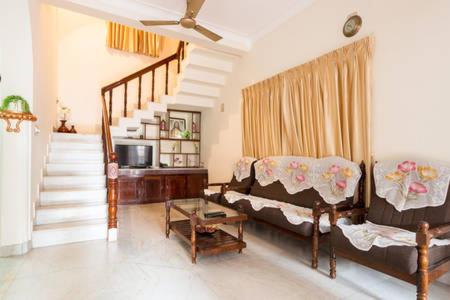a living room with a couch and a staircase at Stay at DBRA 61 Don Bosco Cross Road Vaduthala Ernakulam in Cochin