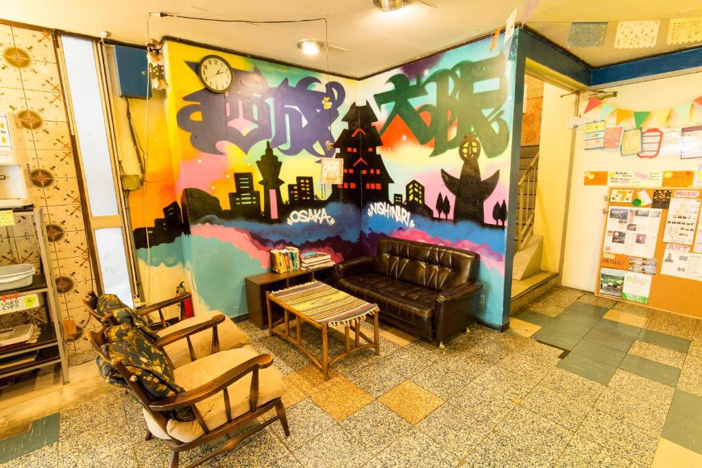 a living room filled with furniture and a painting on the wall at Backpackers Hotel Toyo in Osaka