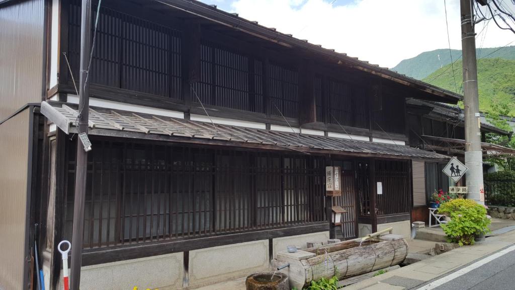 ein asiatisches Gebäude mit schwarzen Fenstern auf einer Straße in der Unterkunft Minshuku Suhara in Okuwa