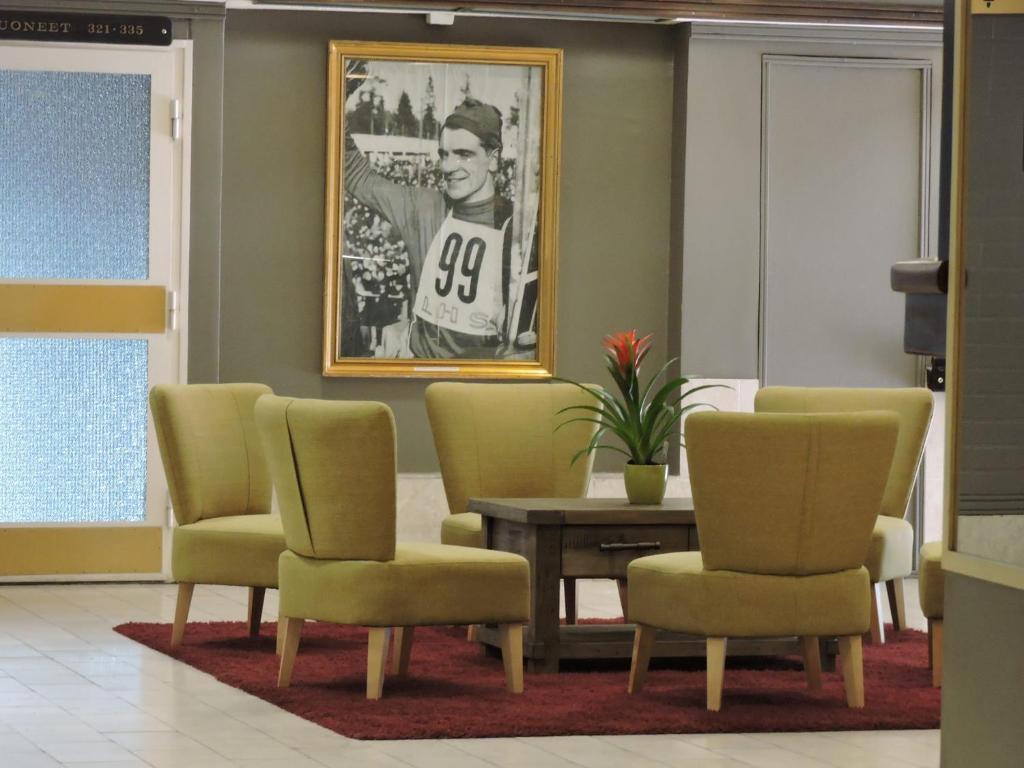 a waiting room with chairs and a table and a picture at Hotelli Pellonhovi in Pello