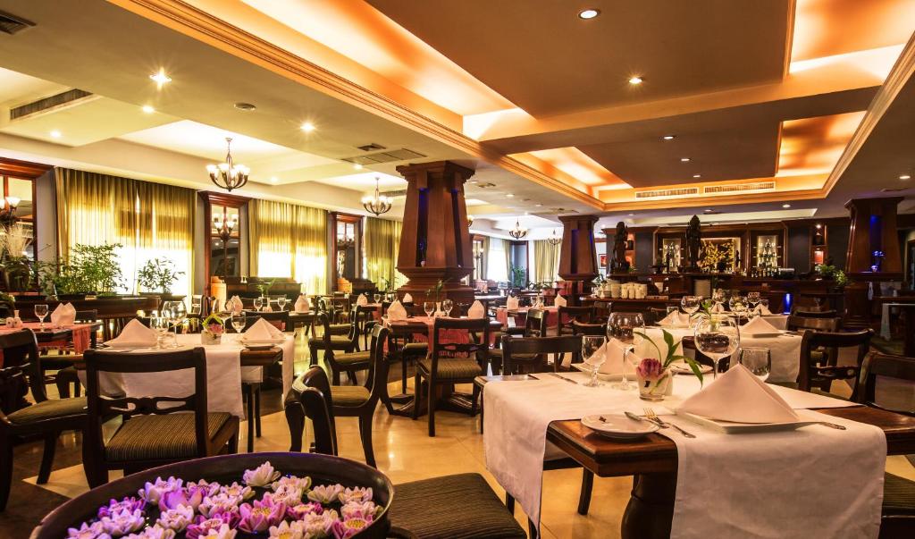 a restaurant with white tables and chairs and flowers at Prince Angkor Hotel & Spa in Siem Reap