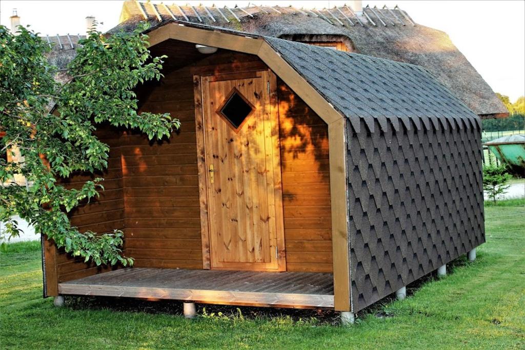 a wooden dog house with a door in the grass at Kalda Camping Valma in Valma