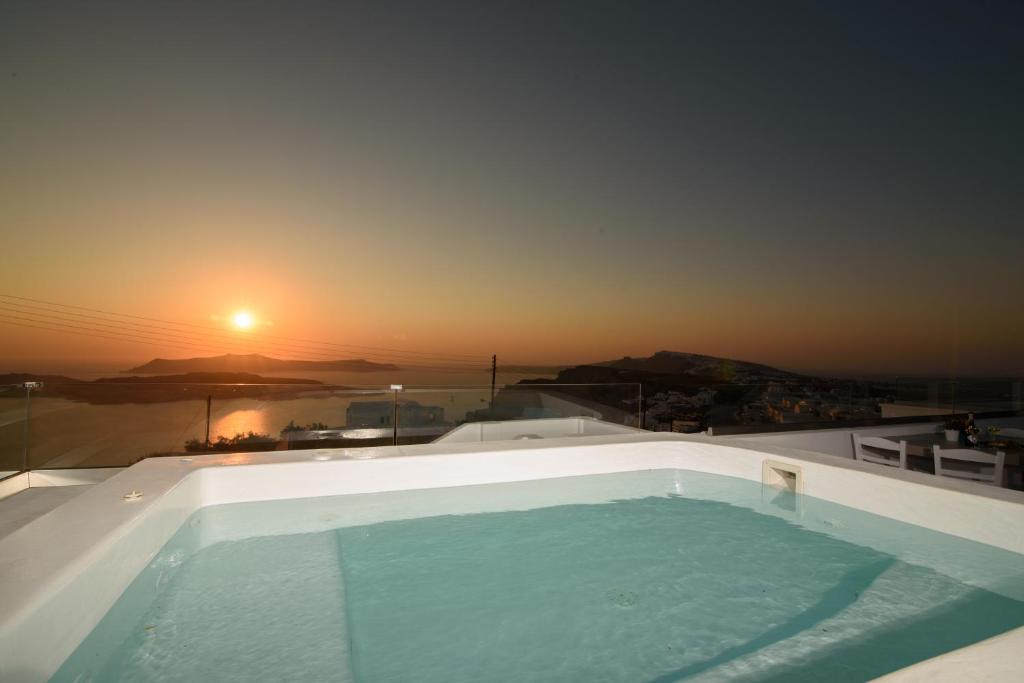 a hot tub on the roof of a house with the sunset at Island View Santorini in Pirgos