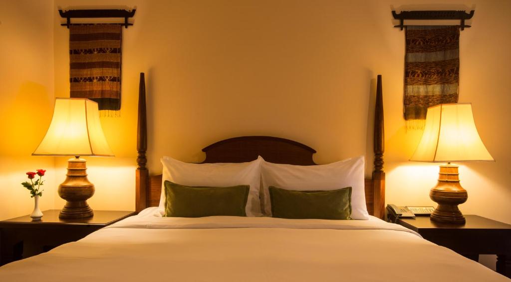 a bedroom with a large white bed with two lamps at Prince Angkor Hotel & Spa in Siem Reap