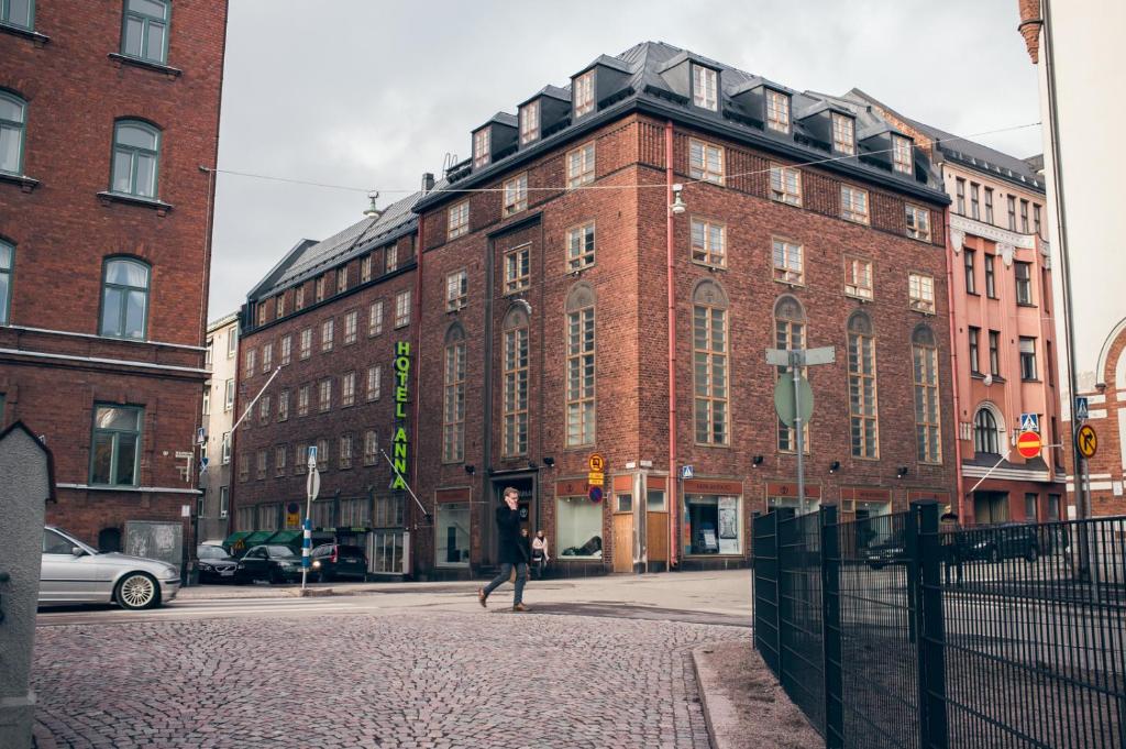 um homem andando em frente a um edifício de tijolos em Hotel Anna em Helsinque