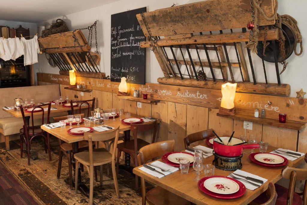 a restaurant with wooden tables and chairs and a chalkboard at Hôtel Restaurant La Ferme du Père François in Les Rousses