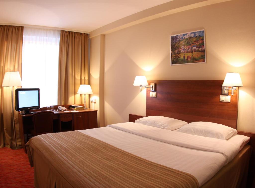 ein Hotelzimmer mit einem großen Bett und einem Schreibtisch in der Unterkunft Maxima Panorama Hotel in Moskau