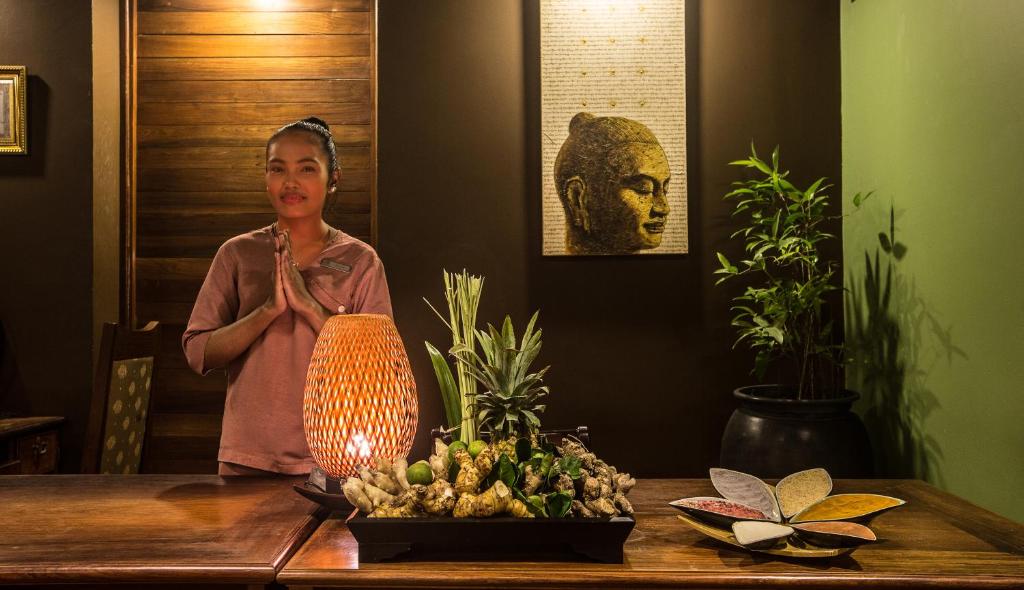 a woman standing next to a table with a vase at Prince Angkor Hotel & Spa in Siem Reap