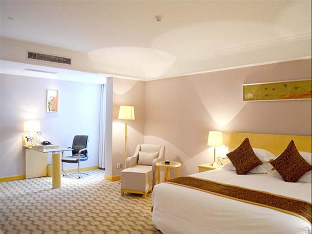 GaoyouにあるHui Fu Jinling Hotelのベッドとデスクが備わるホテルルームです。