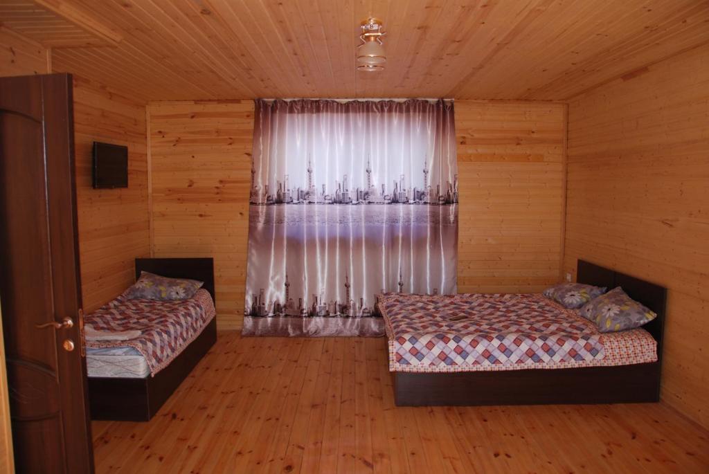 a bedroom with two beds and a window with curtains at Guest house Ozernaya in Cholpon-Ata