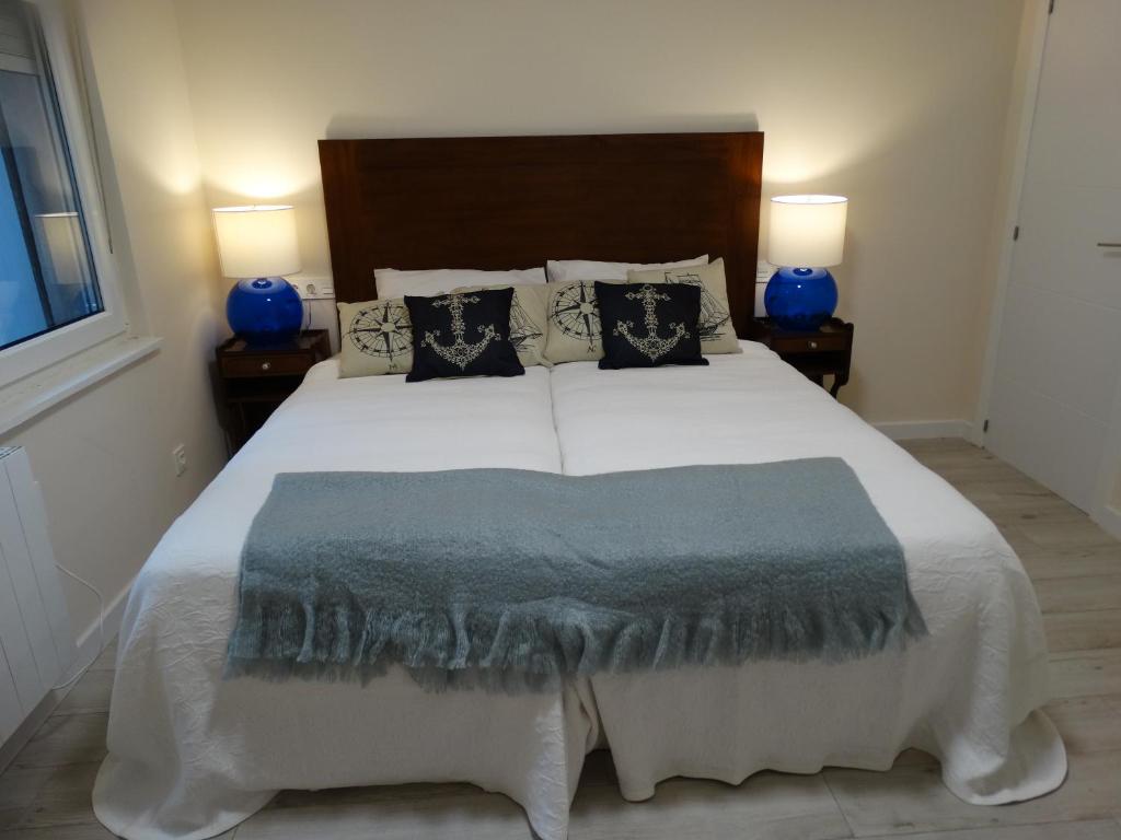 - une chambre avec un grand lit blanc et des oreillers bleus dans l'établissement La Casa Del Marino, à Avilés