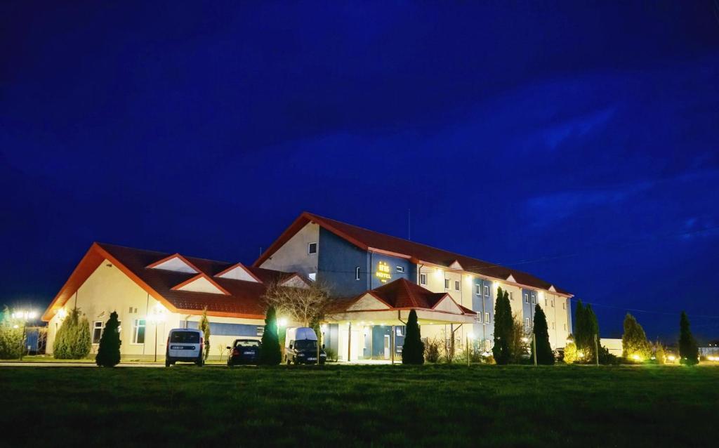a large building with cars parked in a field at night at Iris Hotel in Oradea