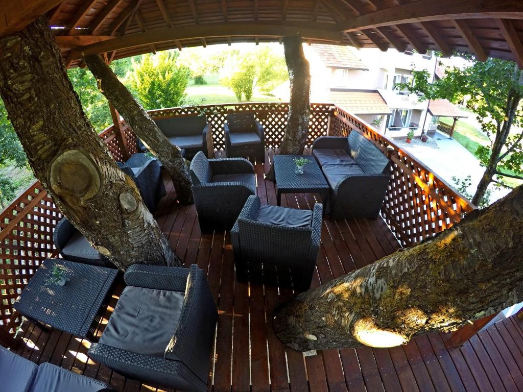 eine Holzterrasse mit Stühlen und einem Baum in der Unterkunft Rooms Villa Ruja in Grabovac