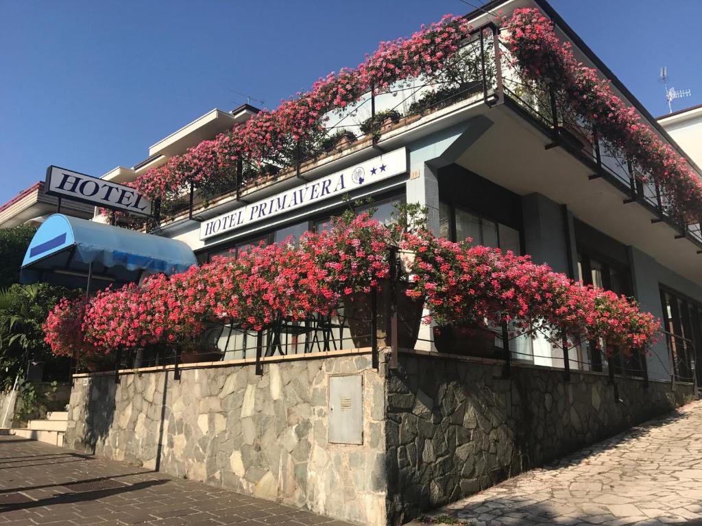 un bâtiment avec des fleurs rouges sur son côté dans l'établissement Hotel Primavera, à Desenzano del Garda